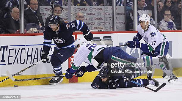 Alexander Edler of the Vancouver Canucks flies over Chris Thorburn of the Winnipeg Jets as he tries to get the puck from Jim Slater as Shawn Mattias...