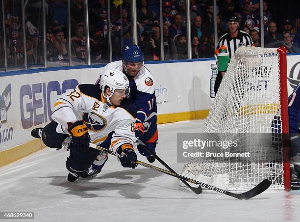 Marcus Foligno of the Buffalo Sabres attempts to wrap the puck arouund the net as he is tripped up by Lubomir Visnovsky of the New York Islanders...