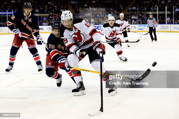 Martin St. Louis of the New York Rangers knocks the puck away from Travis Zajac of the New Jersey Devils in the first period during a game at Madison...