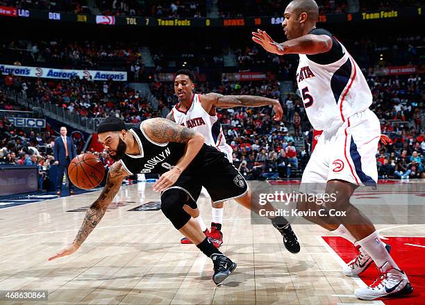 Deron Williams of the Brooklyn Nets loses the ball as he drives against Jeff Teague and Al Horford of the Atlanta Hawks at Philips Arena on April 4,...