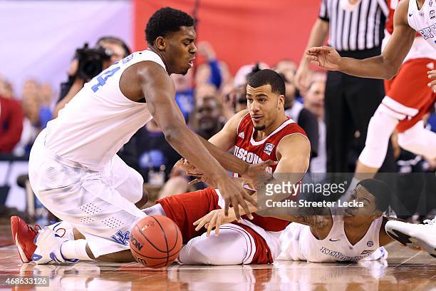 Dakari Johnson and Tyler Ulis of the Kentucky Wildcats fall to the court going for a loose ball with Traevon Jackson of the Wisconsin Badgers in the...