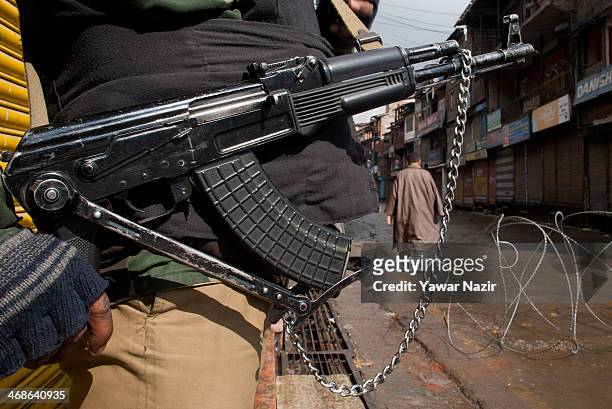 An Indian paramilitary soldier stands guard as a Kashmiri Muslim man negotiates curfew on the death anniversary of Maqbool Bhat on February 11, 2014...