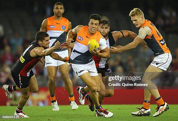 Dylan Shiel of the Giants breaks free from a tackle by Leigh Montagna and Marverick Weller of the Saints during the round one AFL match between the...