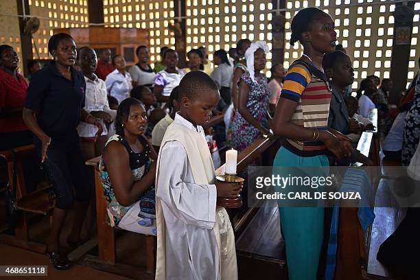 Young altar server holds a candle during a Easter service at the Catholic cathedral in Garissa on April 5 mourning the country's worst ever...