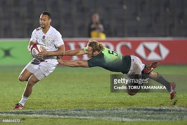 England's Dan Norton dodges a tackle by South Africa's Werner Kok during the final match of the Tokyo Rugby Sevens in Tokyo on April 5, 2015. England...