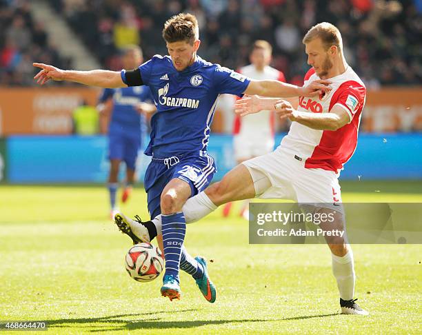 Klaas-Jan Huntelaar of FC Schalke is tackled by Ragnar Klavan of FC Augsburg during the Bundesliga match between FC Augsburg and FC Schalke 04 at SGL...