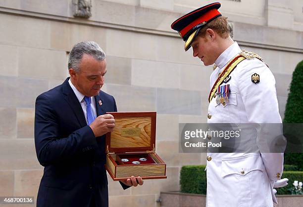 Prince Harry is presented with a gift from Brendan Nelson, Director of the Australian War Memorial, during a visit to the Australian War Memorial on...