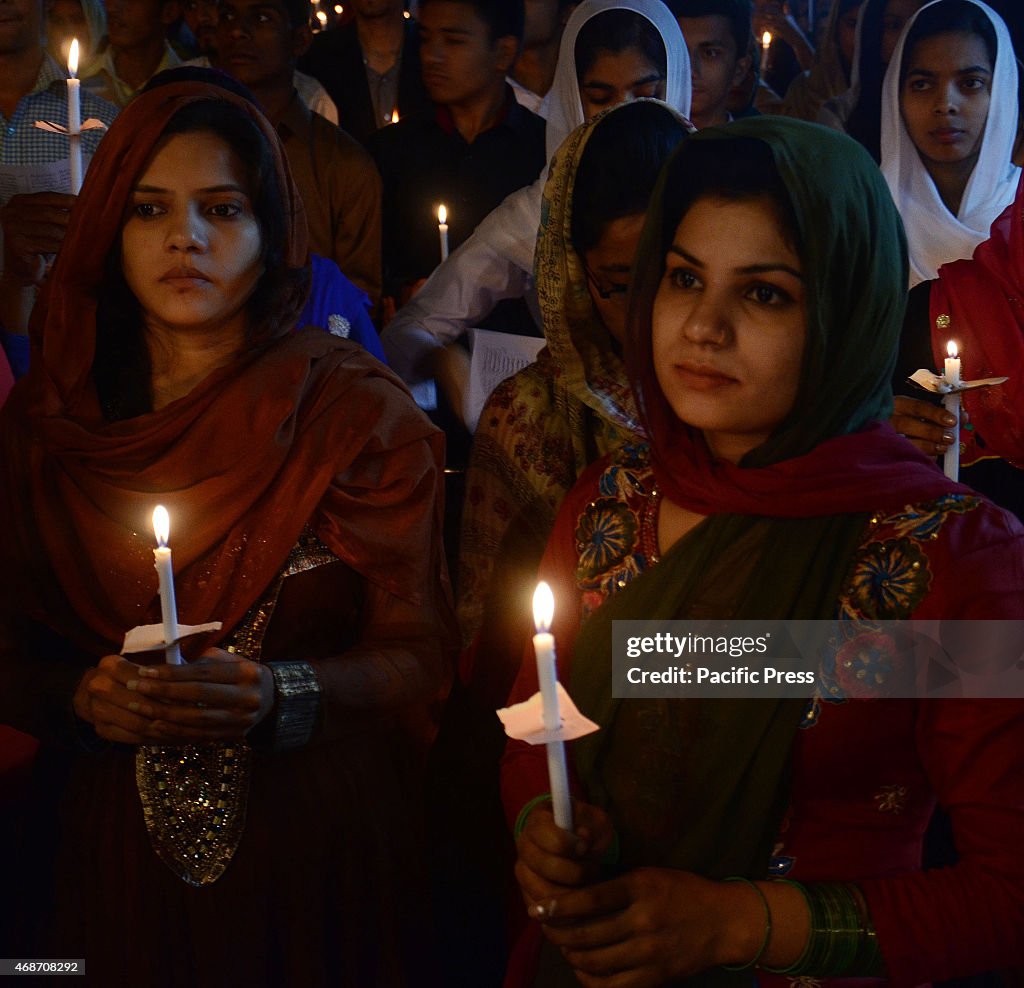 Pakistani Christian worshipers pray and hold candles during...