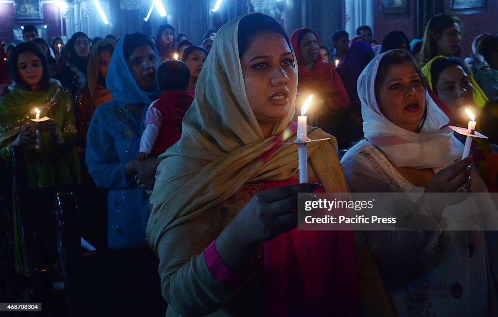 Pakistani Christian worshipers pray and hold candles during...