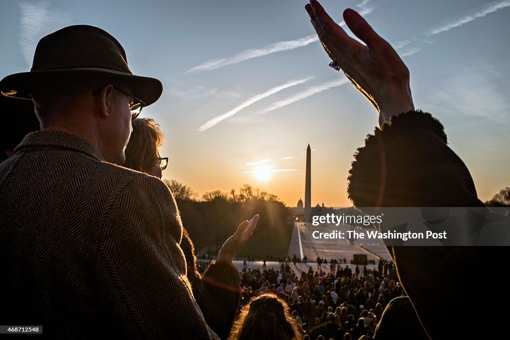 Hands are lifted during an Easter prayer service at the Lincoln Memorial as the sun rises over the Washington Monument on Easter Sunday in Washington...