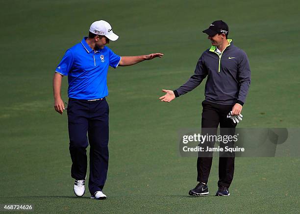 Rory McIlroy of Northern Ireland congratulates Amateur Bradley Neil of Scotland after Neil chipped in from the fairway during a practice round prior...