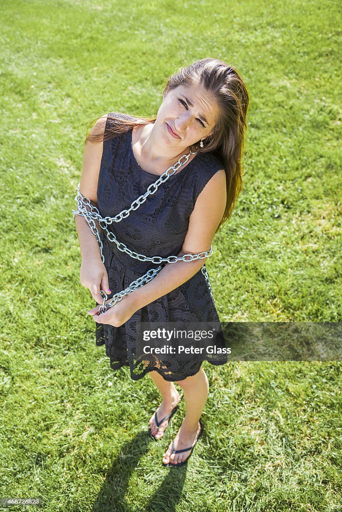 Teen girl, in a park, bound with chains