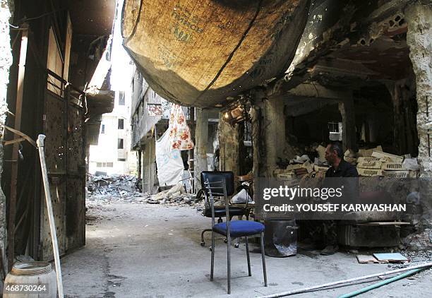 Man sits inside a demolished building in the Yarmuk Palestinian refugee camp in the Syrian capital Damascus on April 6, 2015. Around 2,000 people...