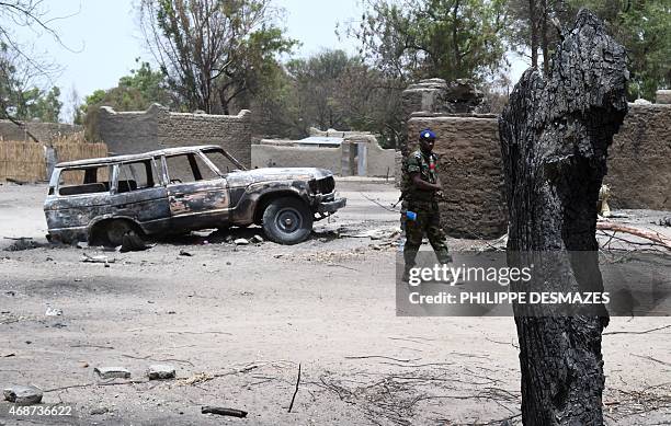 Chadian gendarme walk past burnt houses on April 6, 2015 in N'Gouboua, near Lake Chad in Chad, which was attacked by Islamist group Boko Haram on...