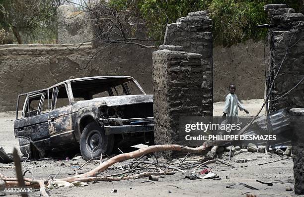 Boy walks past a burnt house and car on April 6, 2015 in N'Gouboua, near Lake Chad in Chad, which was attacked by Islamist group Boko Haram on...