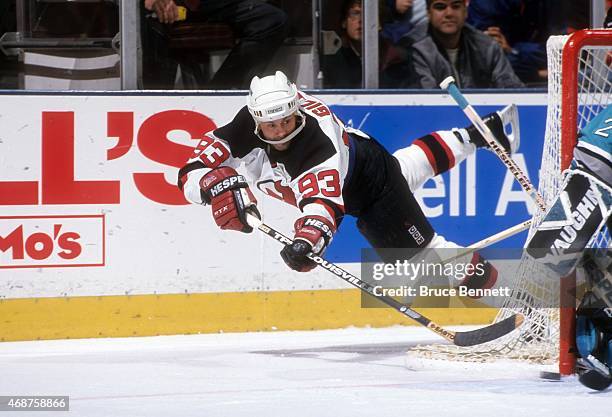 Doug Gilmour of the New Jersey Devils passes the puck to the front of the net while falling to the ice during an NHL game against the San Jose Sharks...