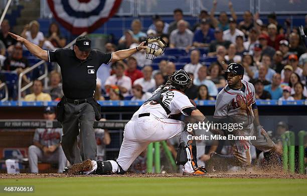 Eric Young Jr. #4 of the Atlanta Braves slides past Jarrod Saltalamacchia of the Miami Marlins to score the go ahead run during Opening Day at...