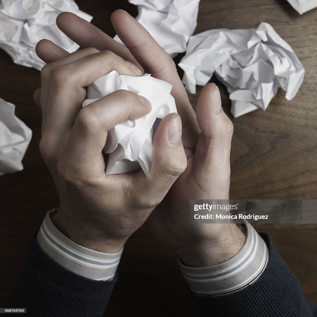 Man's hands crumble writing paper