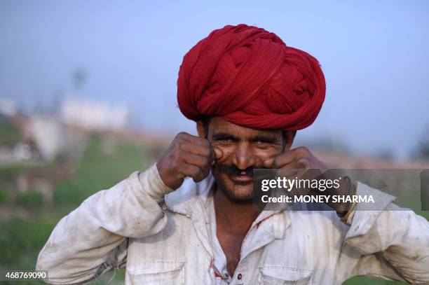 In this photograph taken on March 25 Indian nomadic shepherd Lassa Ram rolls his moustache as he poses at his camp in Sikri in Faridabad some 50kms...