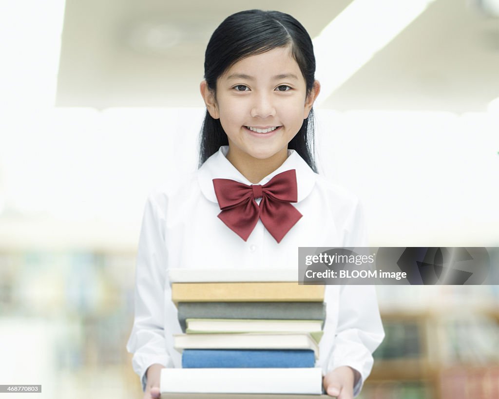 Schoolgirl Holding Stack Of Books