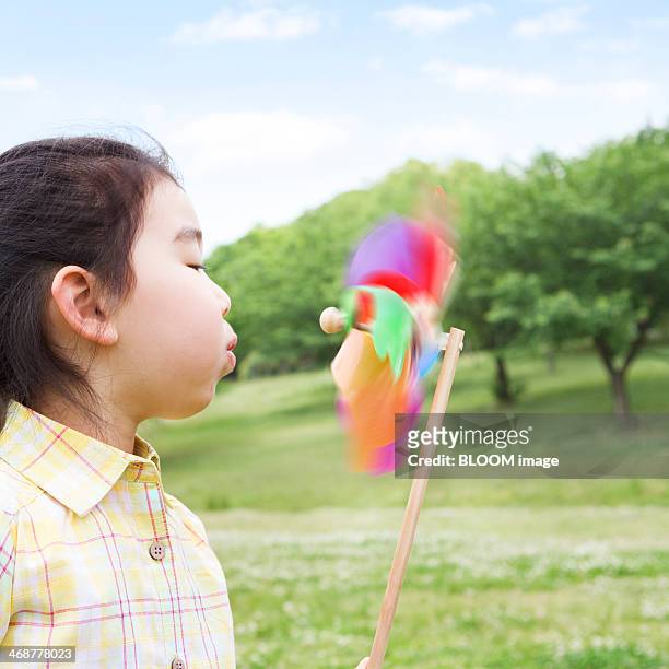 girl blowing pin wheel - asian pin up girls stockfoto's en -beelden