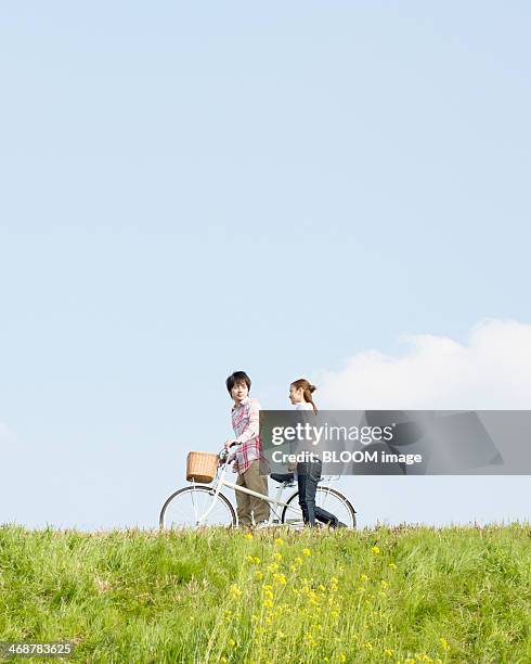 couple walking on grassland - young couple enjoying a walk through grassland stock pictures, royalty-free photos & images