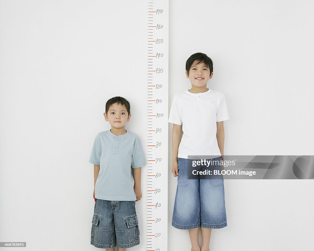 Two Brothers Standing Besides Scale