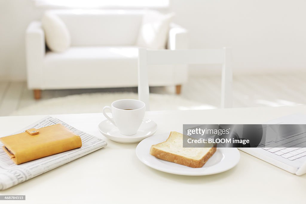 Toast, cup of coffee, personal organizer and newspaper on table