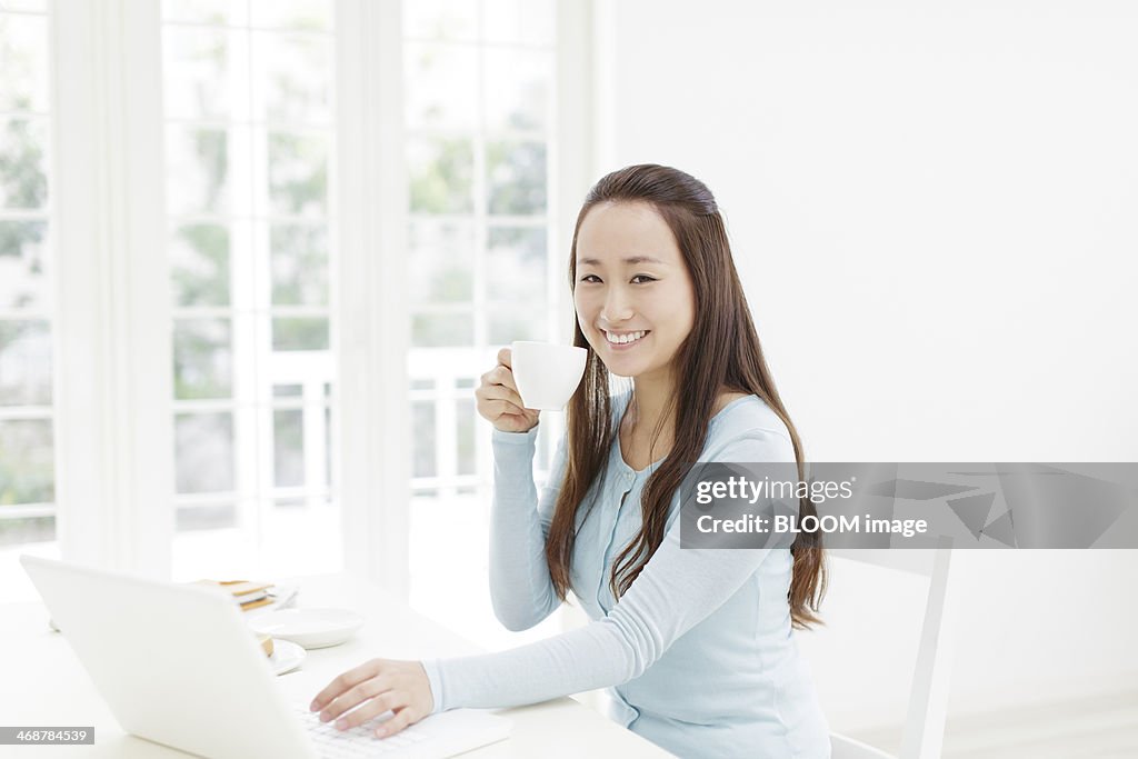 Young woman working on laptop and drinking coffee
