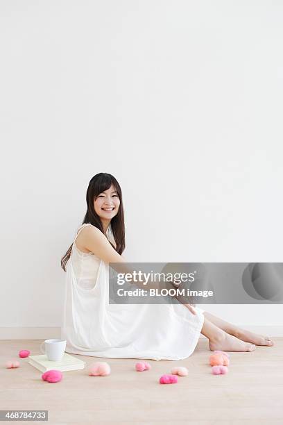 portrait of smiling young woman sitting on floor - hugging knees stock pictures, royalty-free photos & images