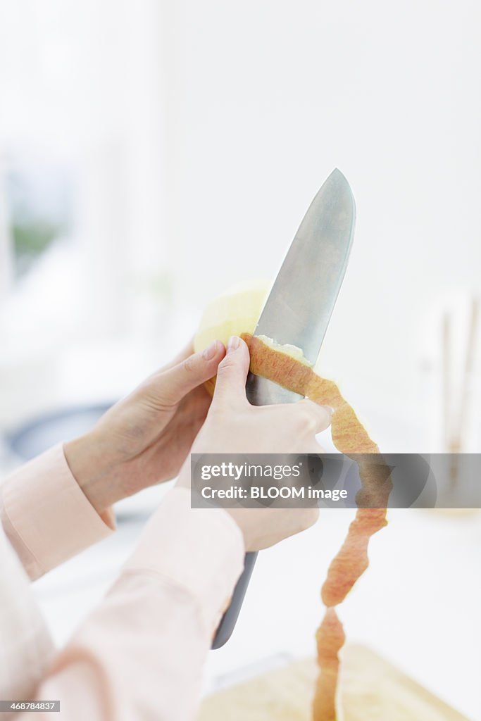 Close up of woman's hands peeling apple in kitchen