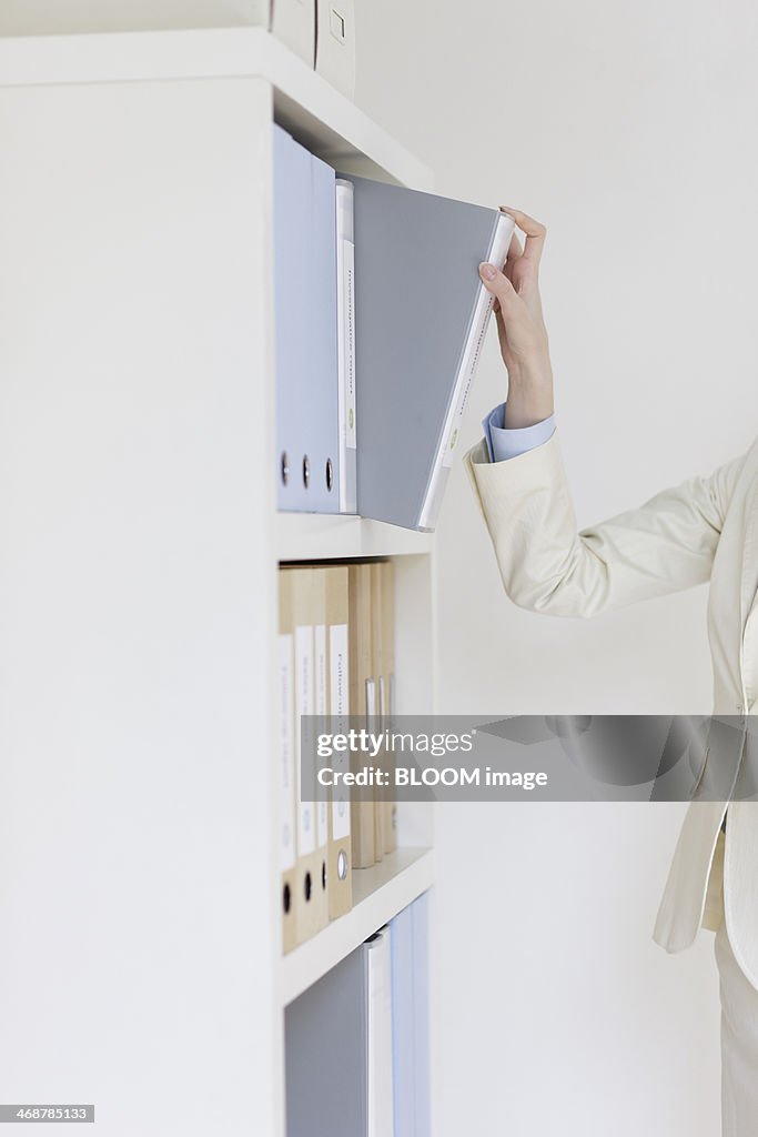 Young businesswoman taking documents out of cabinet