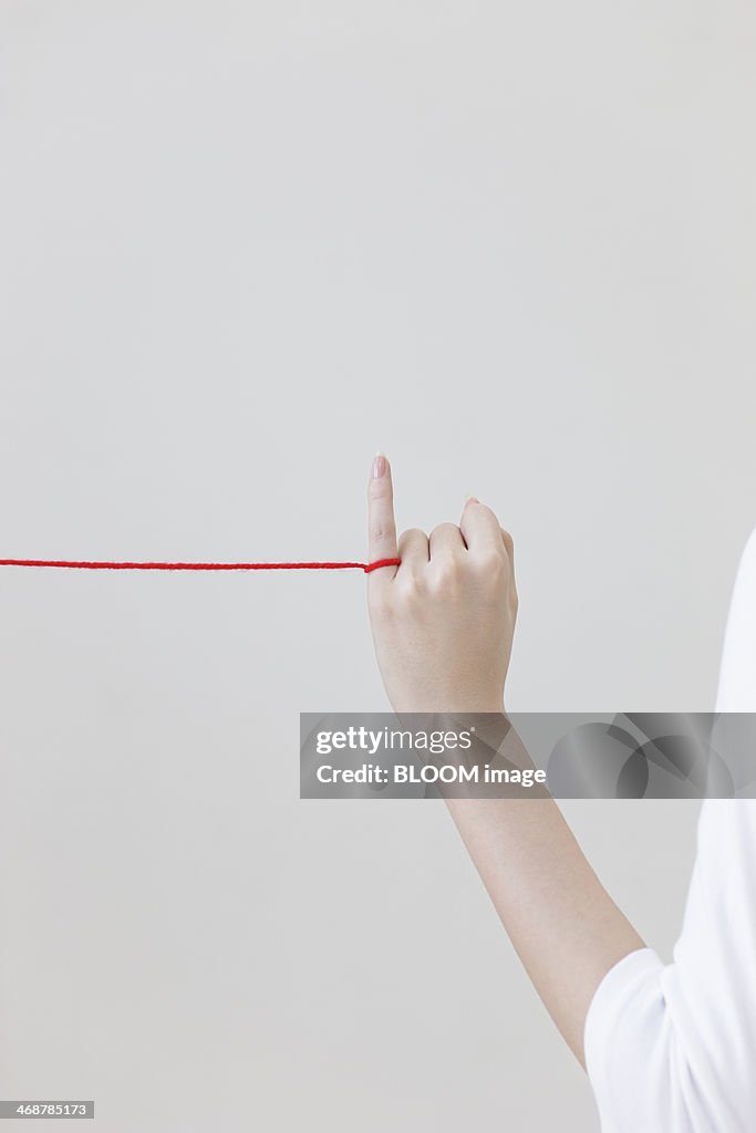 Human hand pulling red string with finger