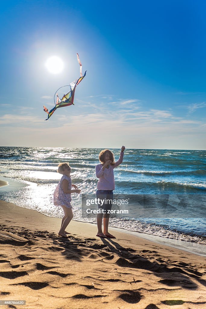 Cute girls flying a kite on a beach