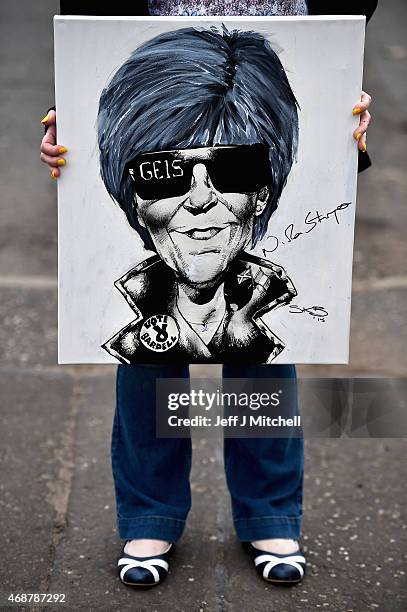 Lorna Craig holds up a cartoon drawn by Stewart Kerr Brown of Scotland's First Minister Nicola Sturgeon outside Forestbank Community Centre on April...