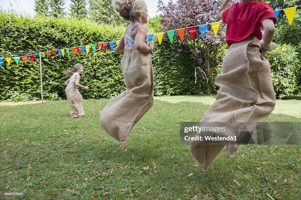 Children having a sack race in garden on a birthday party