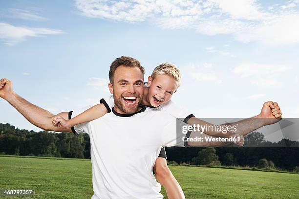 germany, cologne, father and son cheering in football outfit - blonde cheering stock-fotos und bilder