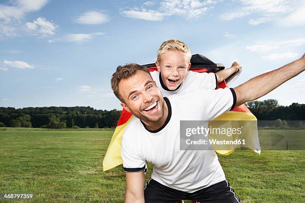 germany, cologne, father and son cheering in football outfit - blonde cheering stock-fotos und bilder