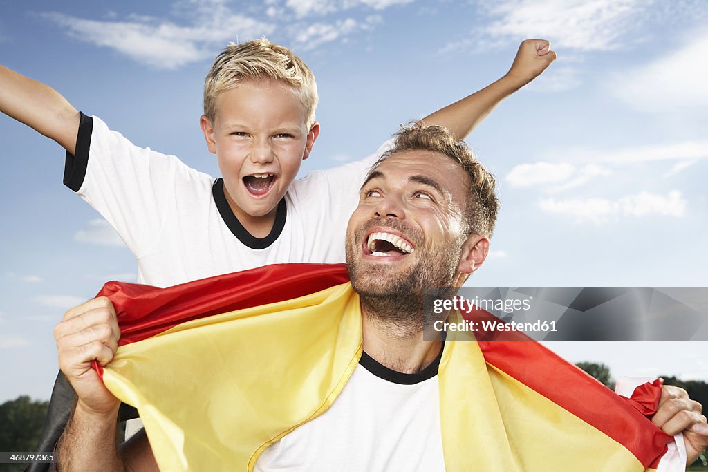 Germany, Cologne, Father and son cheering in football outfit