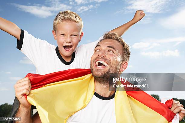 germany, cologne, father and son cheering in football outfit - soccer germany stock pictures, royalty-free photos & images