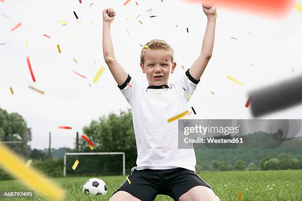 boy in soccer jersey cheering on soccer pitch - blonde cheering stock-fotos und bilder