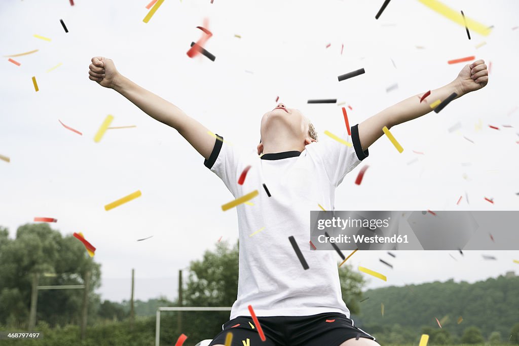 Boy in soccer jersey cheering on soccer pitch