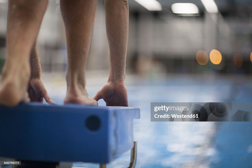 Swimmer on starting block at indoor swimming pool