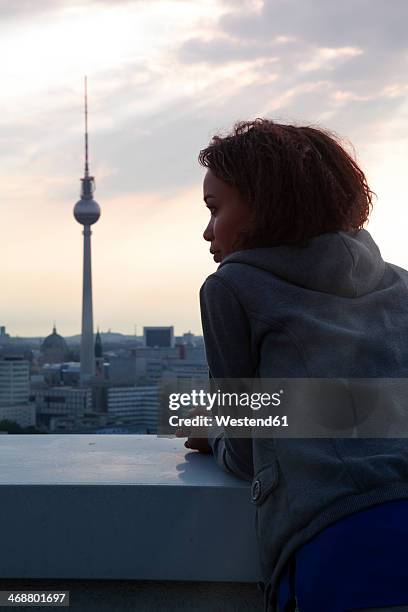 germany, berlin, young woman on rooftop terrace, looking at view - berliner fernsehturm stock-fotos und bilder