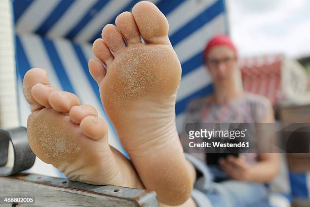 germany, lower saxony, east frisia, langeoog, woman reading e-book at the beach - female soles stock-fotos und bilder