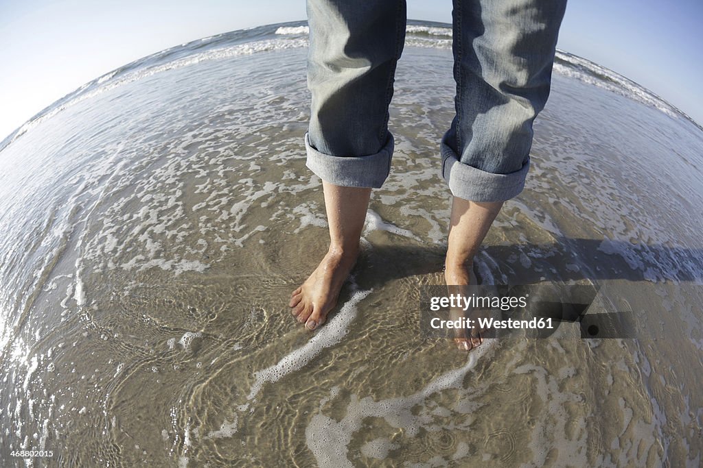 Germany, Lower Saxony, East Frisia, Langeoog, feet of a woman at the beach
