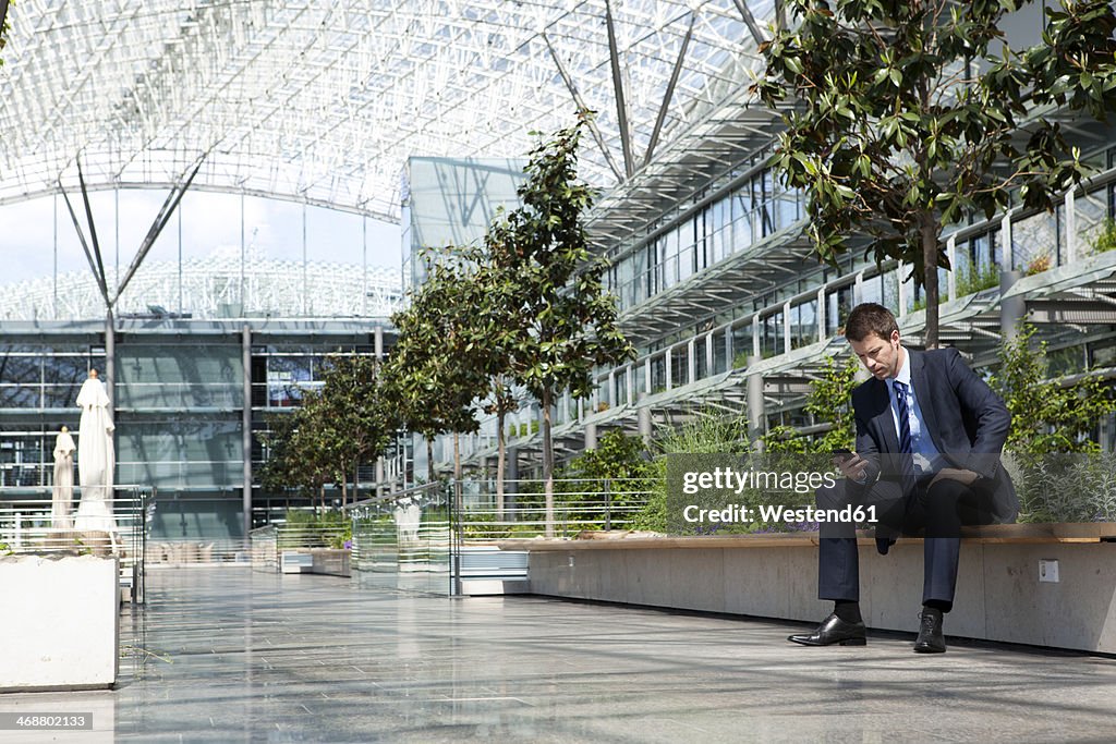 Businessman with cell phone in courtyard