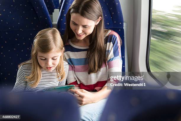 mother and daughter reading book in a train - bambino treno foto e immagini stock