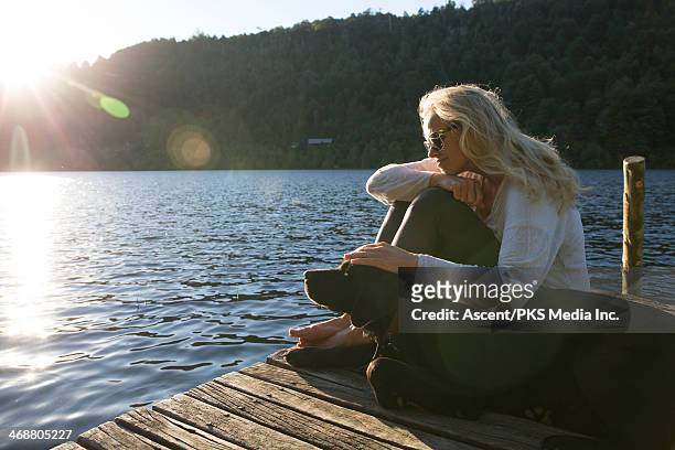 woman pats dog on lake pier, sunrise - woman pier stock pictures, royalty-free photos & images