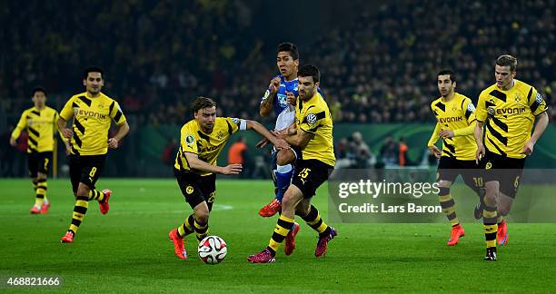 Roberto Firmino of 1899 Hoffenheim is challenged by Marcel Schmelzer of Borussia Dortmund and Sokratis Papastathopoulos of Borussia Dortmund during...